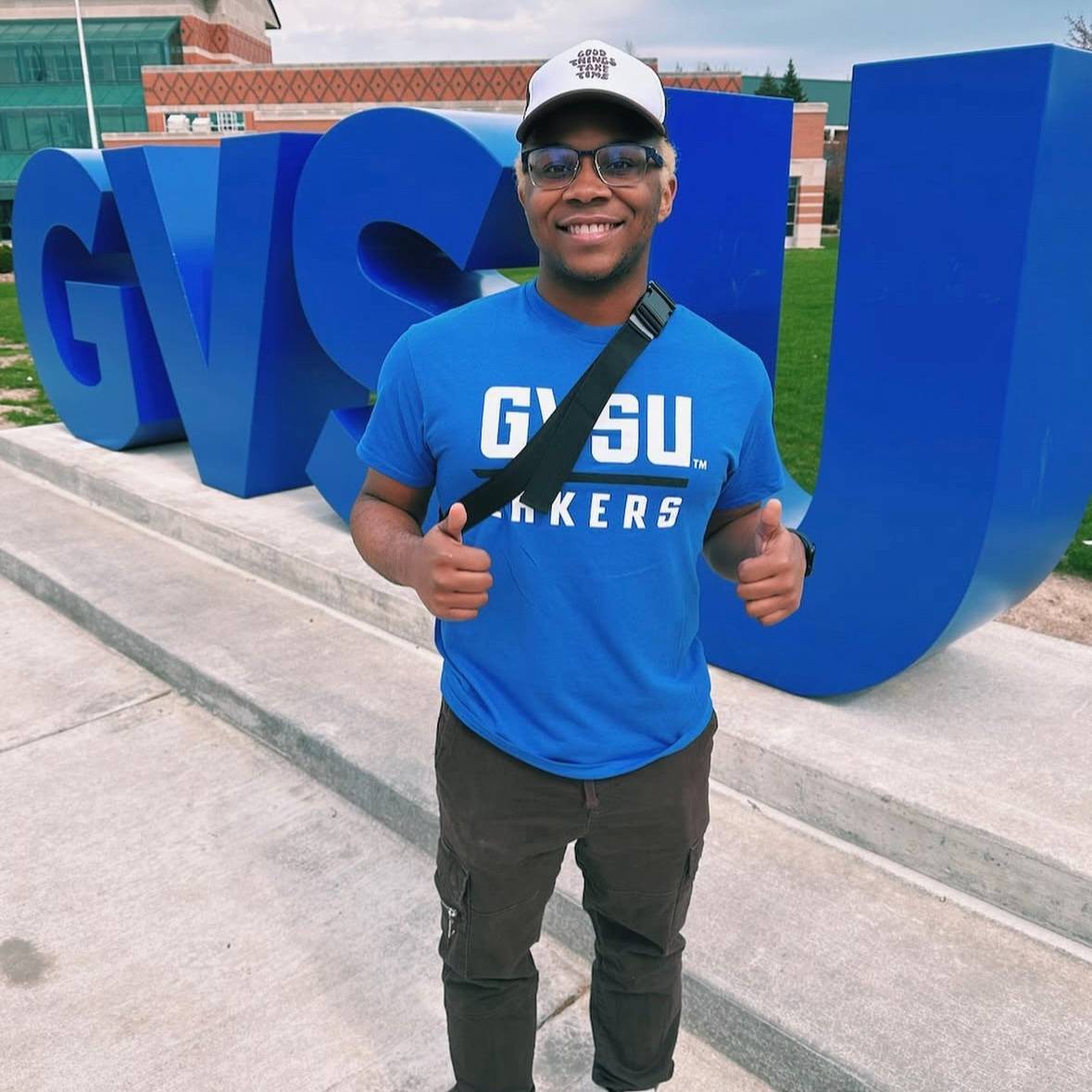 student in front of the GVSU letters